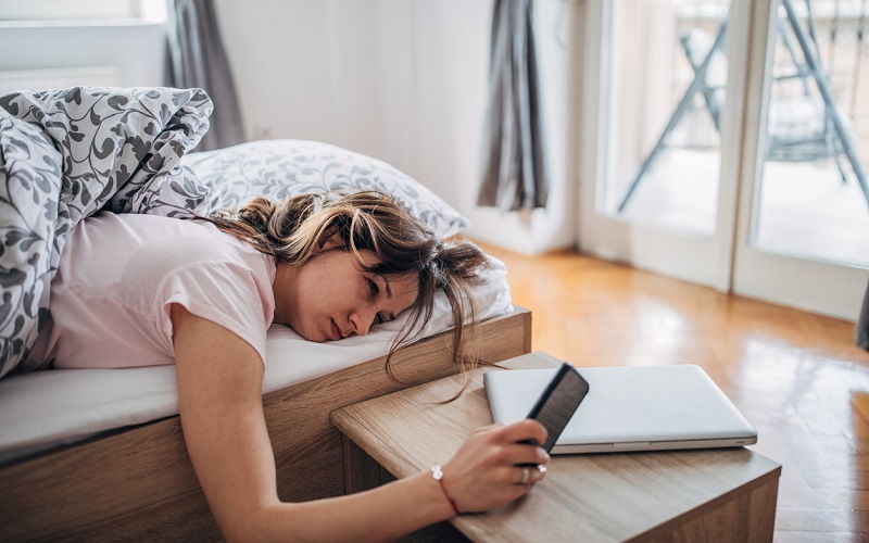 Una mujer tumbada en la cama mirando el móvil